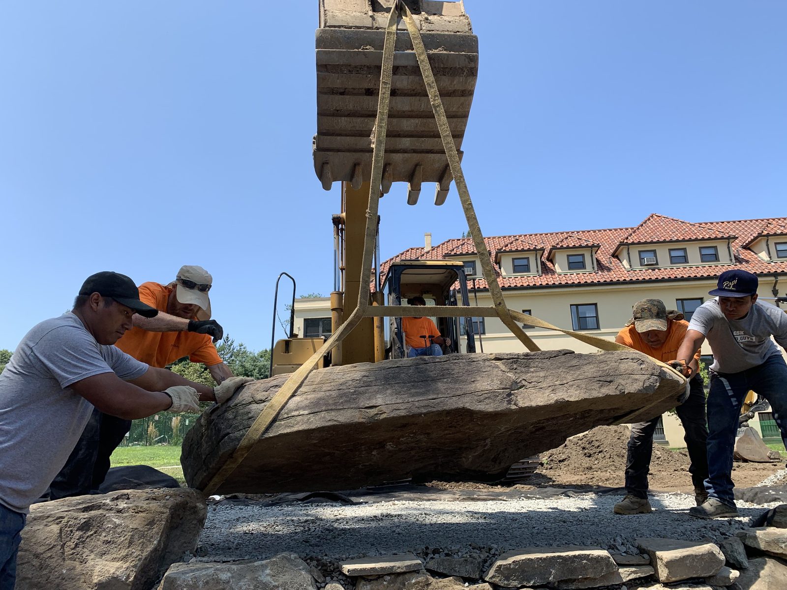 Professional pond crew placing stone correctly on a backyard build
