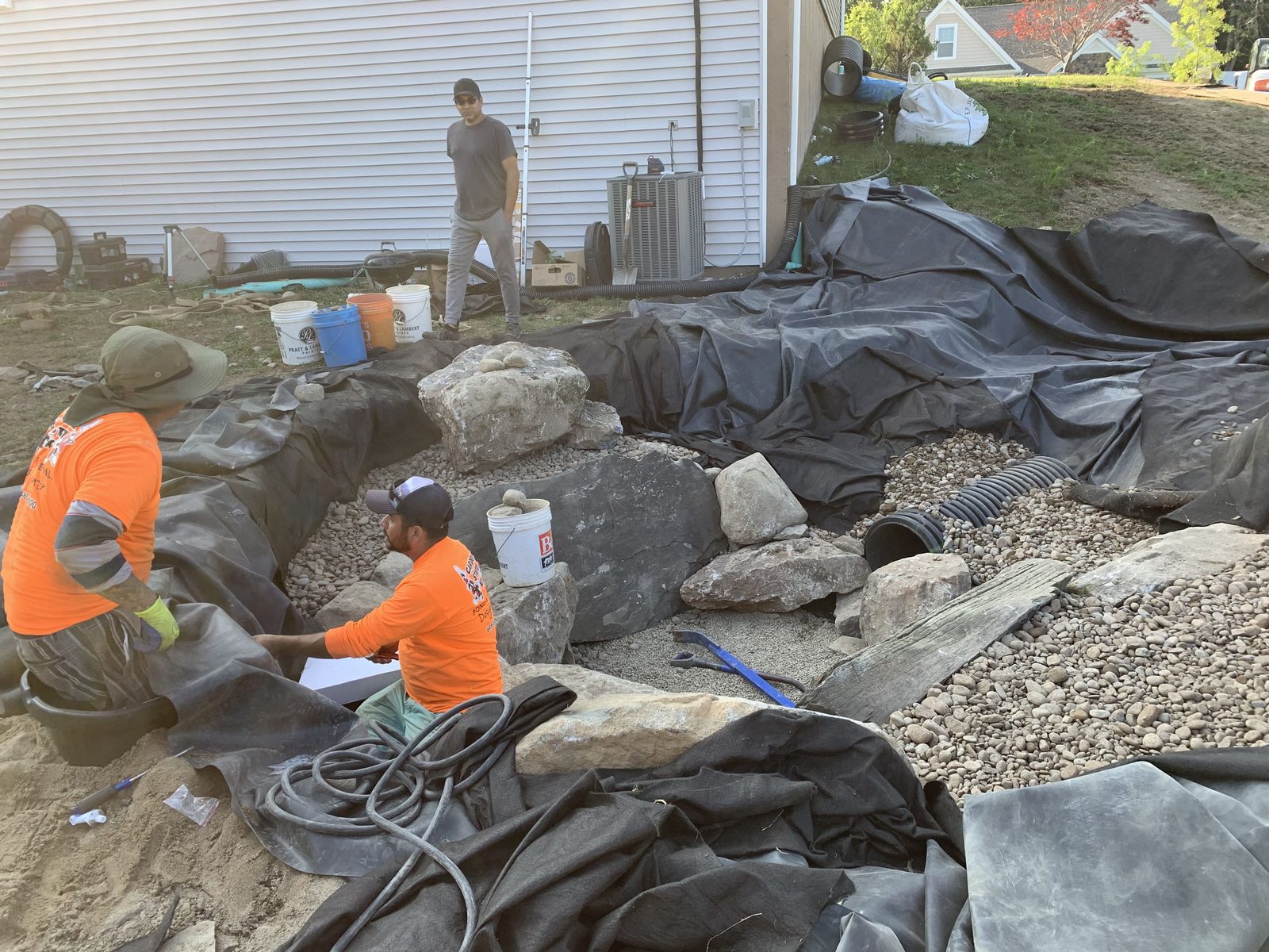 Liner and underlayment being set during a backyard pond build