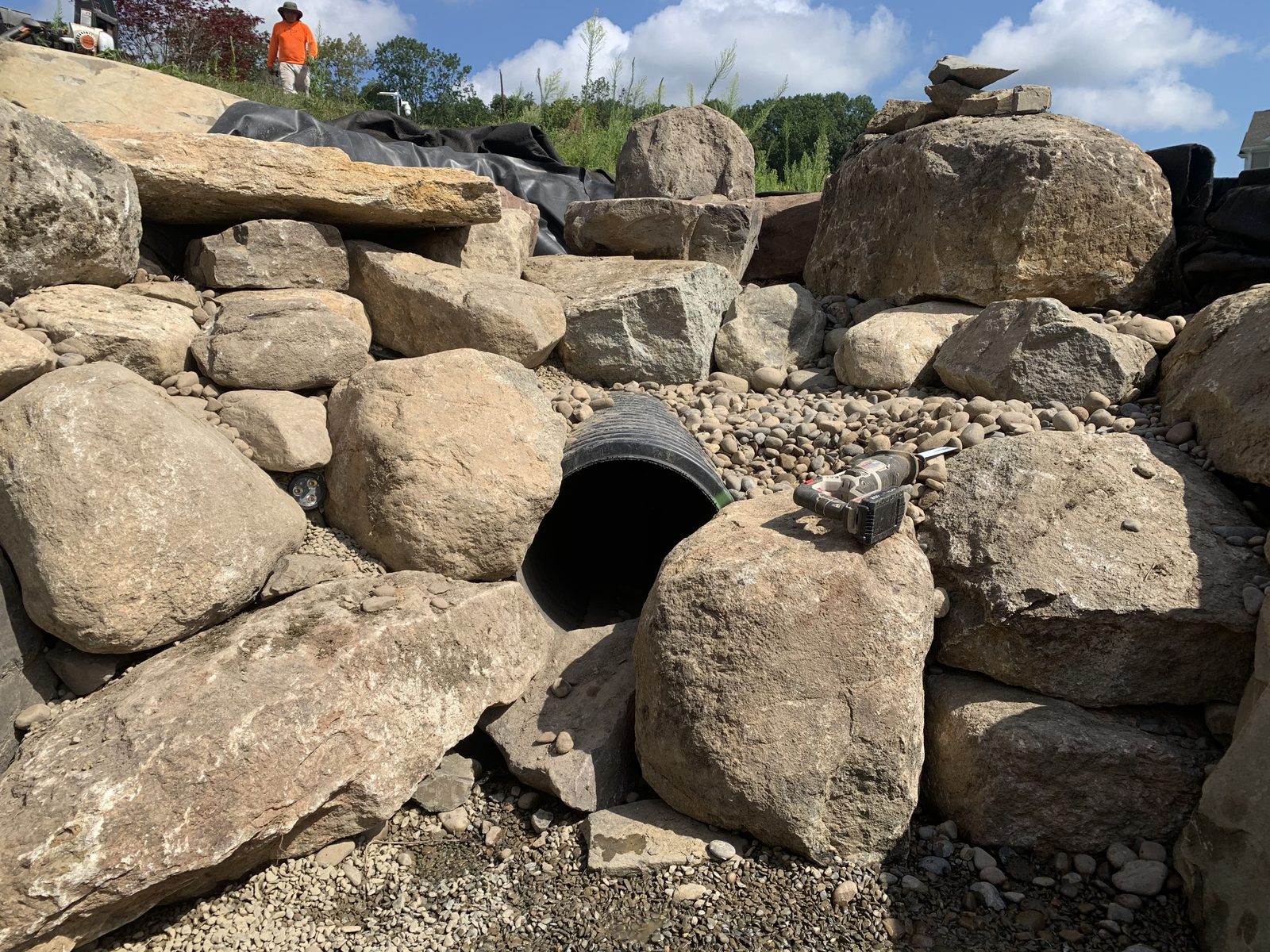 Boulder and pipe work during construction of a backyard pond waterfall