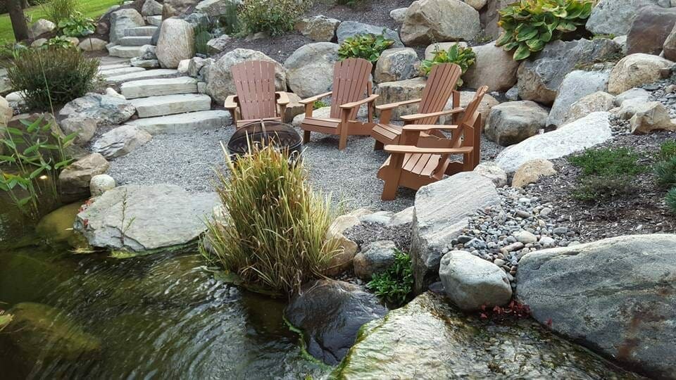 Quiet seating area beside a stone stream in a backyard water garden