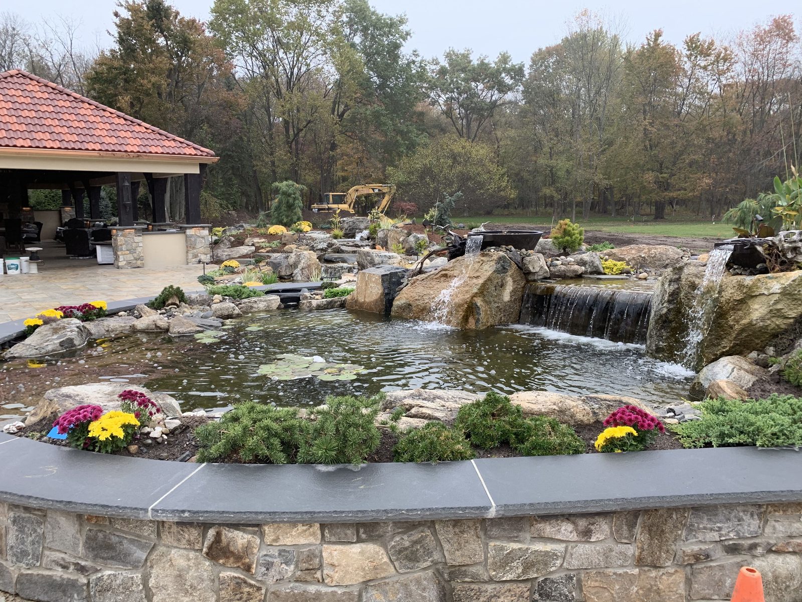 Tranquil backyard pond surrounded by seasonal flowers and stonework