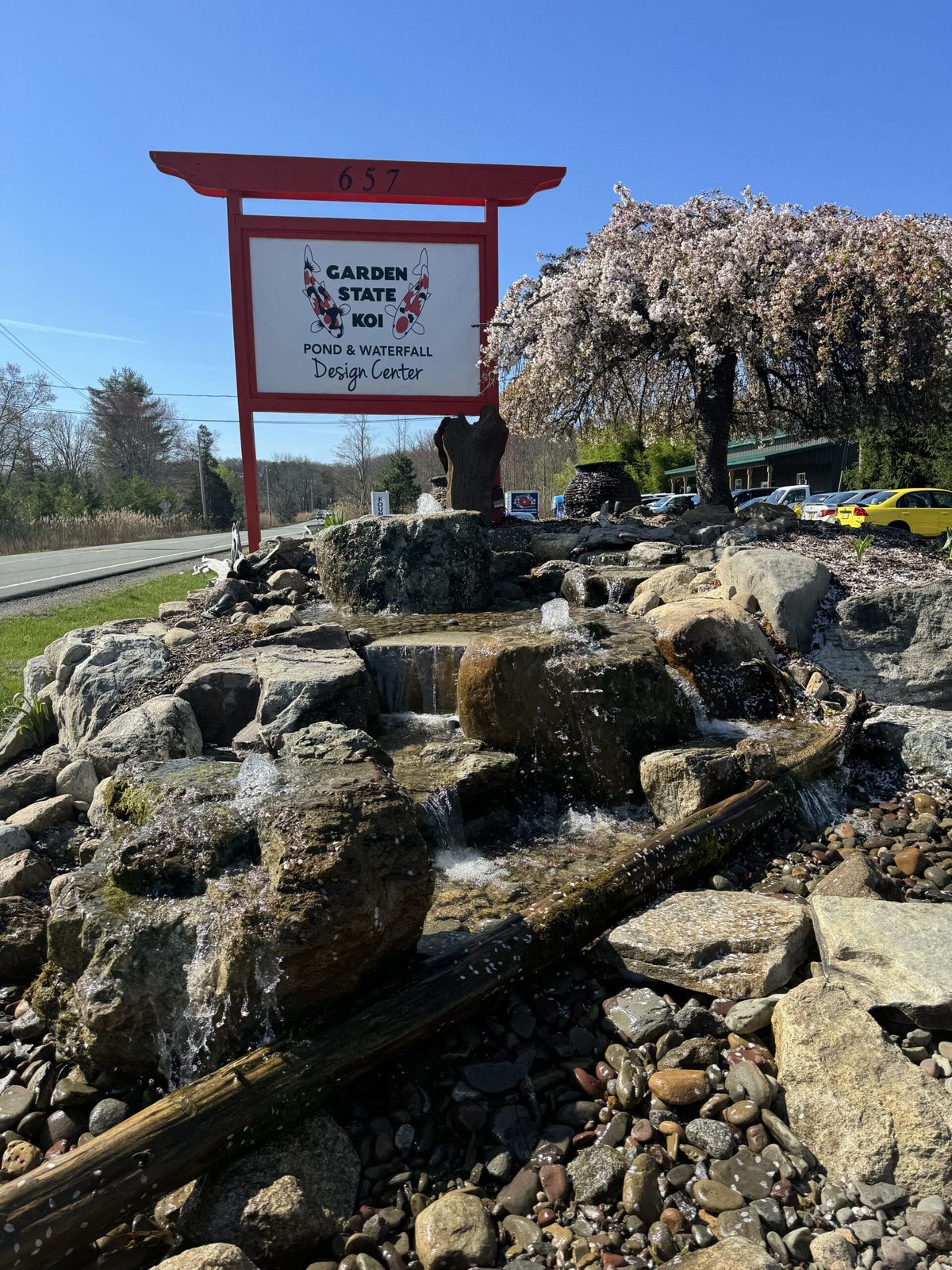 Bubbling stone waterfall cascading through natural boulders beside the Garden State Koi display garden