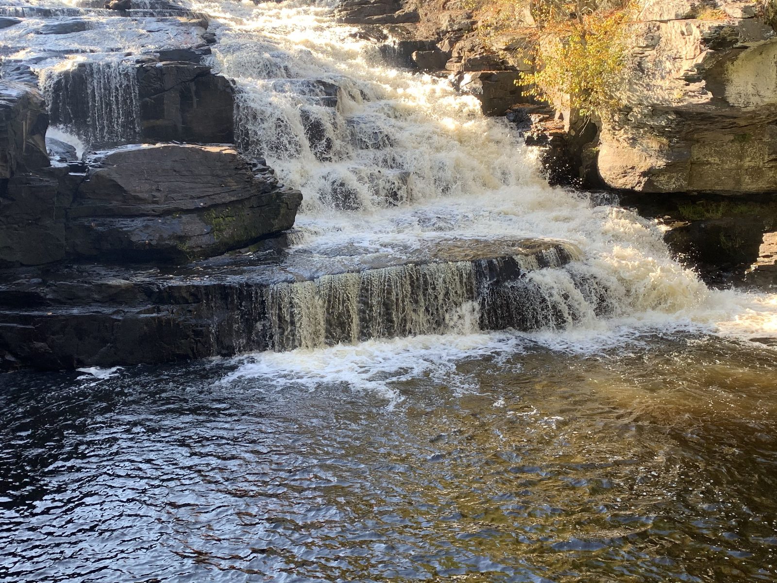Crystal clear pond water tumbling over a clean rock waterfall